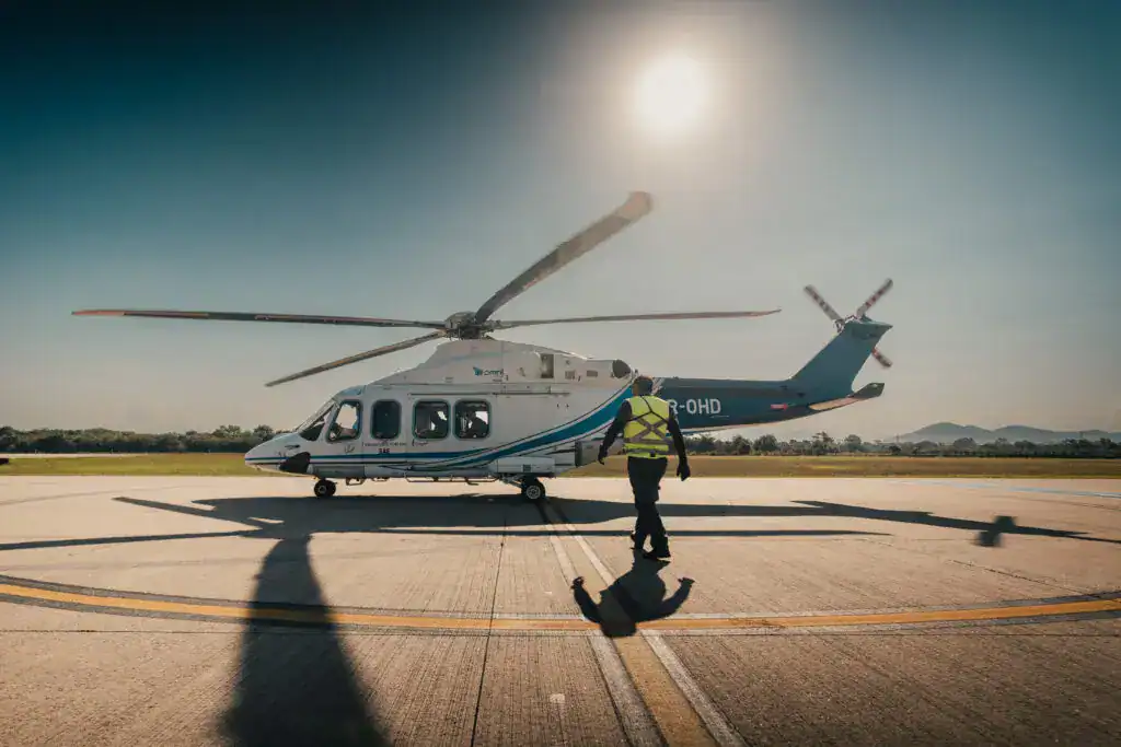 helicopter on the ground with sun behind and worker