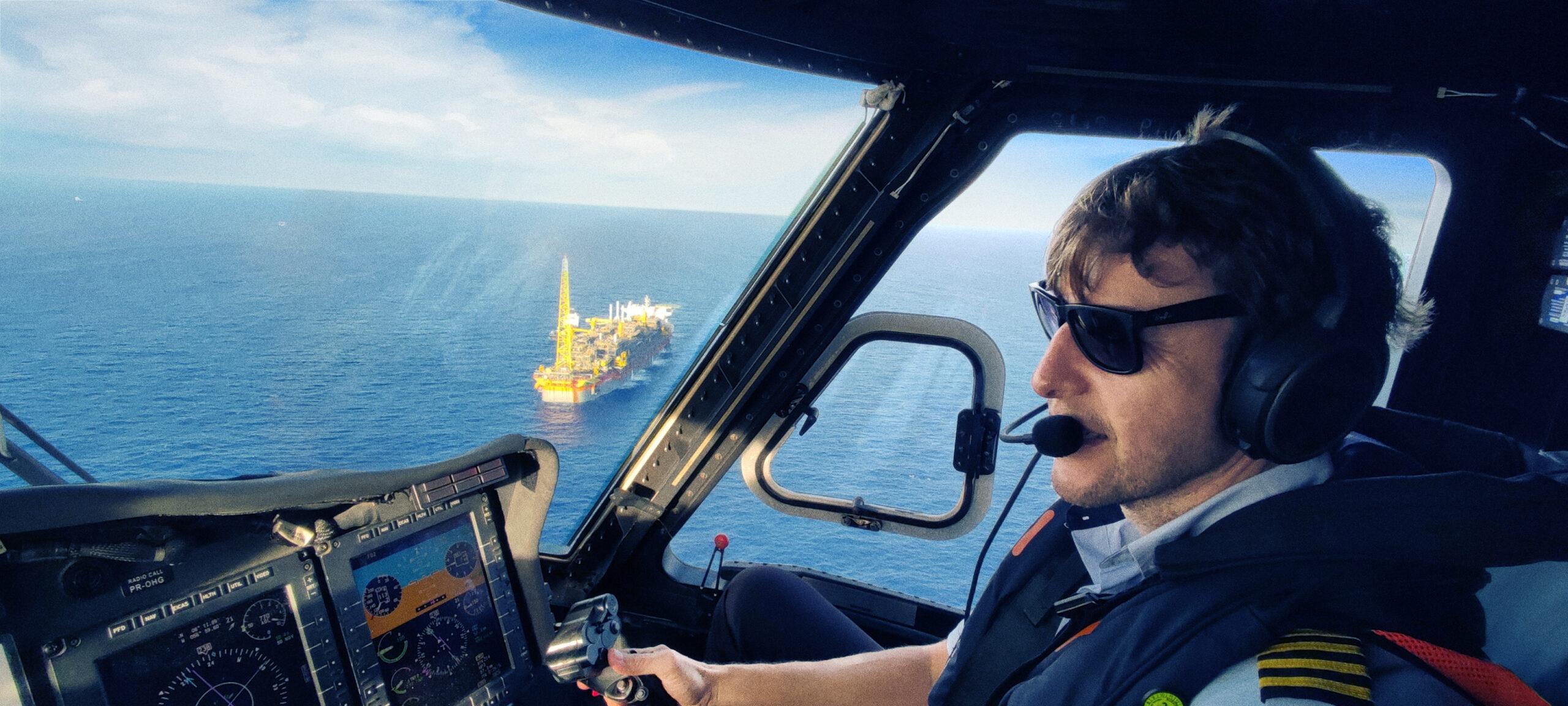 image of pilot flying helicopter over ocean